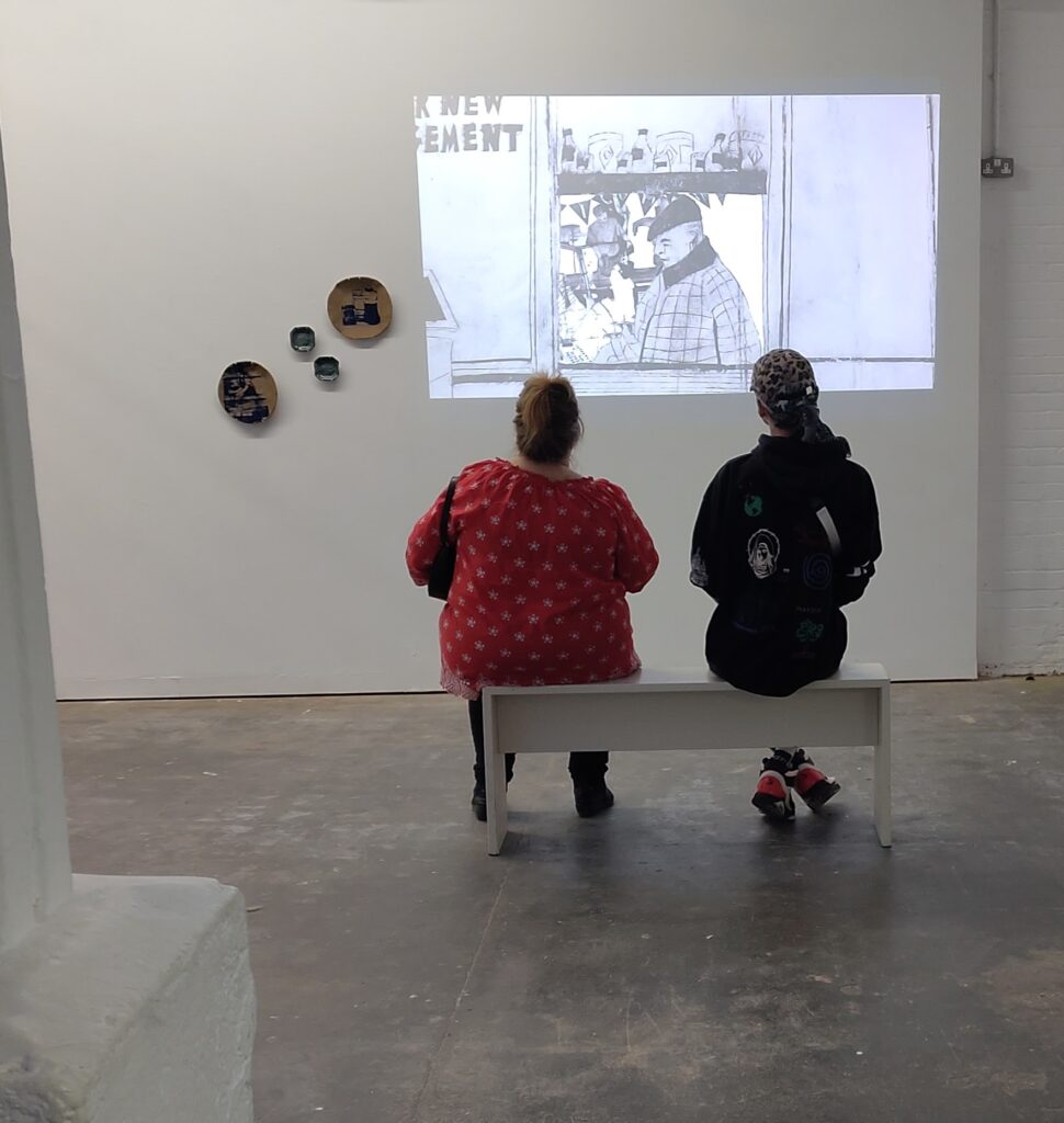 Two people watch the animation Noosh-e-jaan at Humber Street gallerty Hull